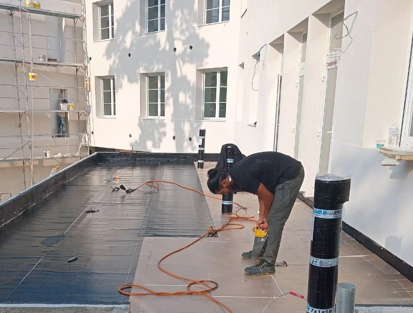 Pose d'une membrane d'étanchéité bitumineuse noire sur un toit-terrasse à Paris par l'entreprise Etanch